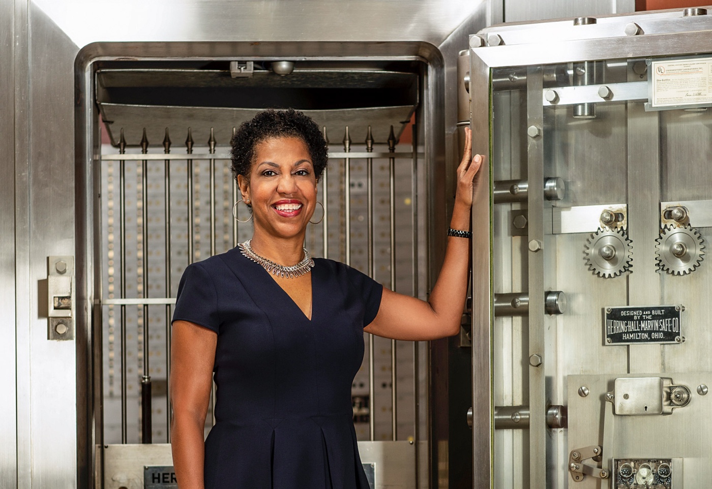 Image of Teri Williams standing in front of an open bank safe.